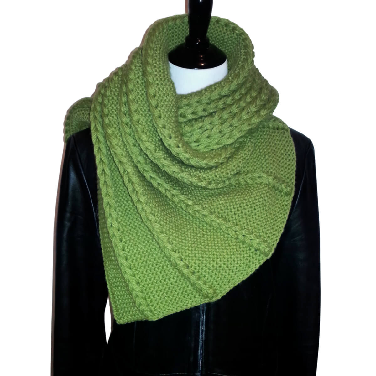 A dress form in a black leather coat with a rectangular shawl wrapped and tucked around it. The yarn is grass green and knit in the garter stitch with 5 vertical sections of chunky chains made with several strands of yarn in each chain.