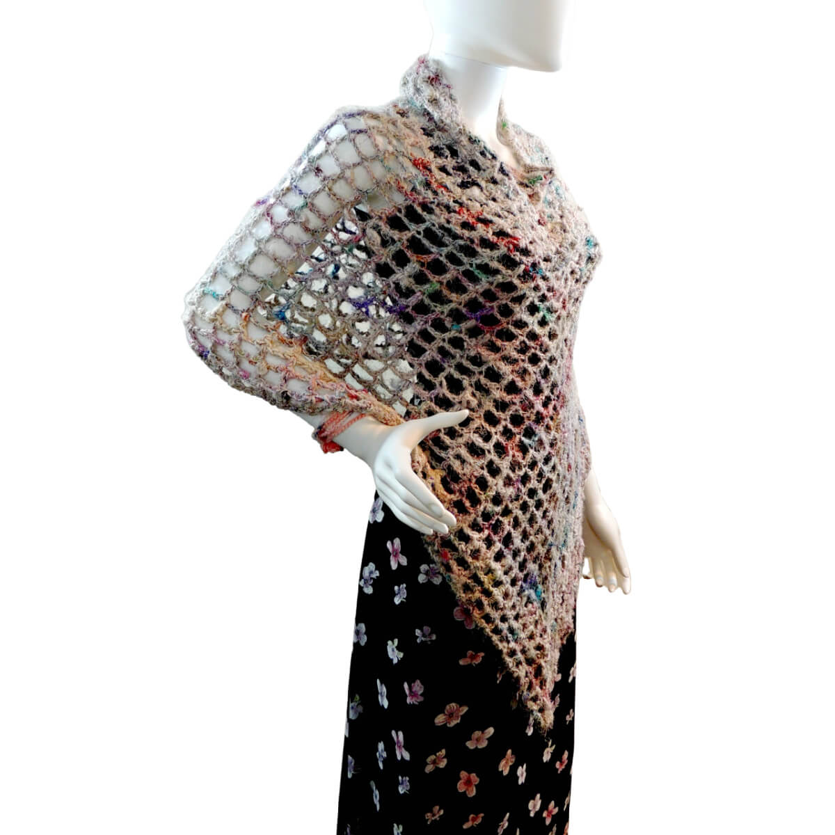 Side front of a mannequin wearing a black skirt, black tank top, and a crochet mesh poncho with one point that hangs about finger-tip length while the opposite side hangs about waist length. The short side is in back, and the long side hangs in front.